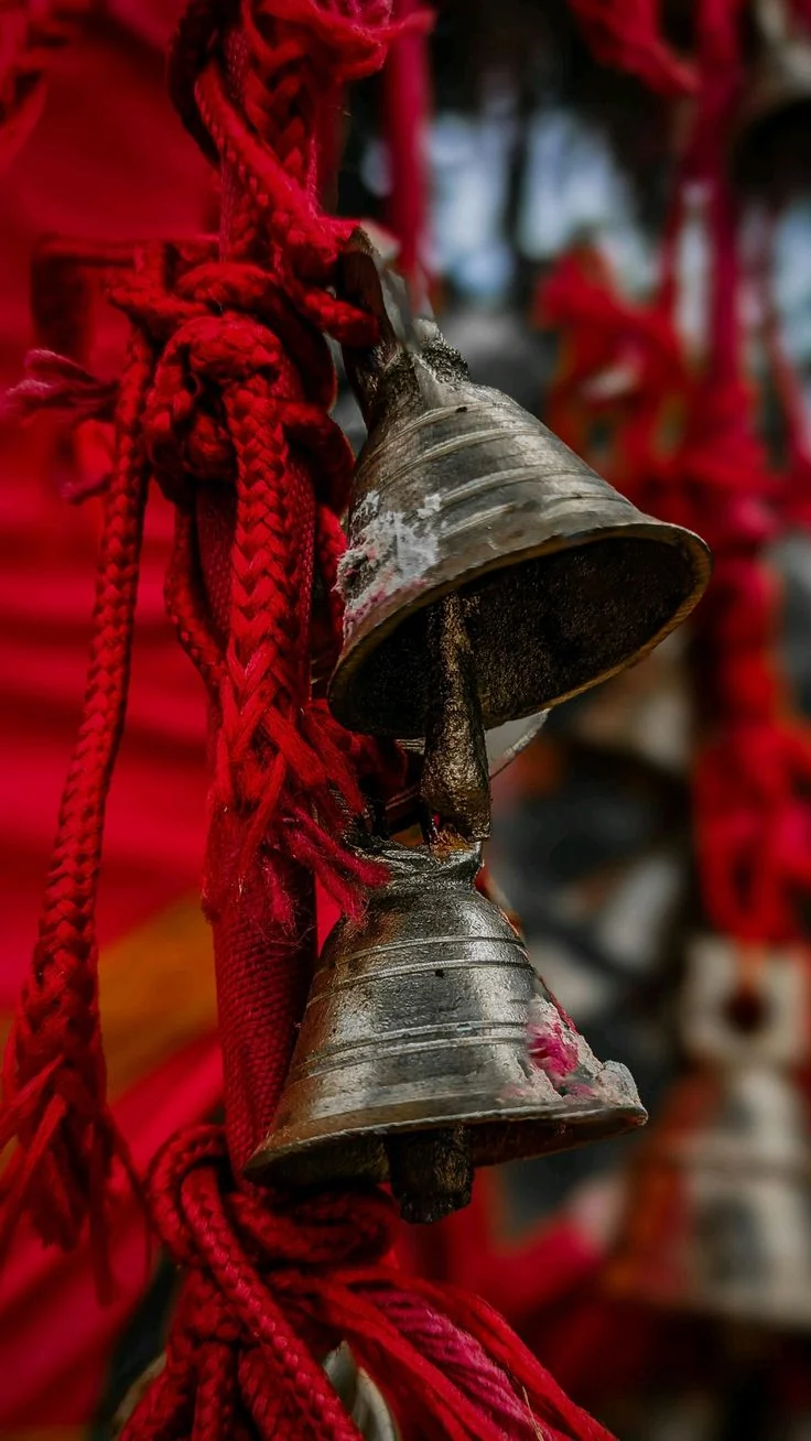 Two brass temple bells tied with red thread